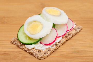 Whole Grain Crispbread with Fresh Cucumber, Egg, Cream Cheese and Radish on Bamboo Cutting Board. Easy Breakfast. Quick and Healthy Sandwiches. Crispbread with Tasty Filling. Healthy Dietary Snack