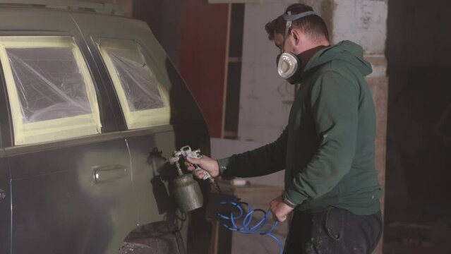 Respirator masks, Safety masks, Mask wearing. Man with respirator working on painting car using spray tool.