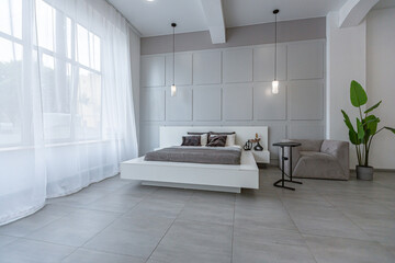 stylish bright modern bedroom interior with decorative niches with LED lighting and a huge panoramic window in gray and white colors and geometric shapes