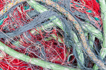green marine rope and tangled red fishing net close-up in. pile.