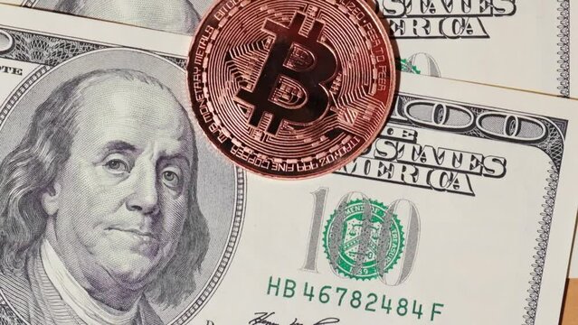 Bitcoin gold coin on bills of 100 dollars. Bitcoin mining trading concept. BTC golden money spinning around. Worldwide virtual internet Cryptocurrency or crypto digital payment system. Digital coin