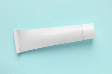 Tube of ointment on light blue background, top view. Space for text