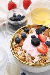 Tasty granola, yogurt and fresh berries in bowl on white table, closeup. Healthy breakfast