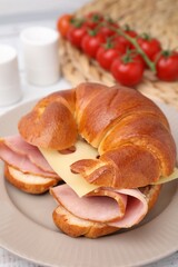 Tasty crescent roll with ham and cheese on table, closeup