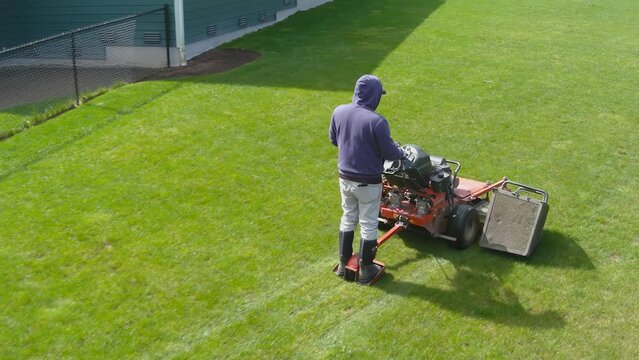 Landscaper mowing the lawn of a modern American suburban home with a standing mower