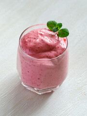 Healthy Strawberry or Raspberry Cream mousse in glass on a white wooden table with mint leaves. Delisious summer dessert. Top view, close up, vertical