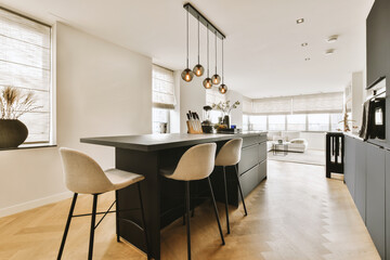 a kitchen and dining area in a modern home with wood flooring, white walls, black cabinets and...