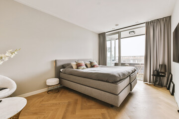 a bedroom with hardwood flooring and large windows overlooking the cityscapet is in front of the bed
