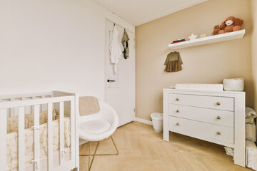 a baby's room with a cribt in the corner and a teddy bear hanging on the wall