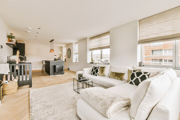 a living room with white couches and fireplace in the center of the room there is a large window that looks out onto the