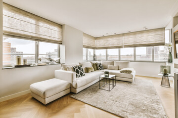 a living room with hardwood flooring and white couches in front of large windows looking out onto the city