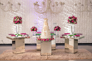 a wedding cake and trays of chocolate brigadeiro on top of a glass table