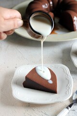 Pouring vanilla vla over a slice of chocolate pudding. On a small white vintage plate. Selective focus
