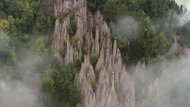 Aerial view tilting through fog, revealing the Piramidi di terra, in south Tyrol, Italy