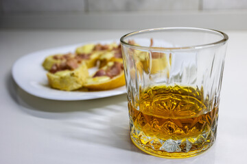 glass of whiskey with snacks on the background