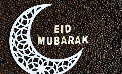 Fototapeta na wymiar A crescent moon and Eid mubarak on top of coffee beans, Eid Al Fitr concept Selective focus