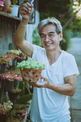 asian holding hanging houseplant pot toothy smiling with happiness face standing outdoor