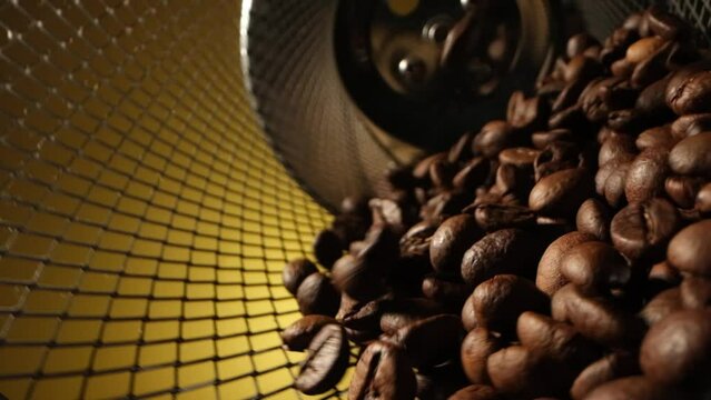 Close up slow motion cinematic beautiful shot of brown roaster coffee beans spinning in an iron cage. High quality footage for advertising. Roasted coffee is a tonic for thinking and creativity