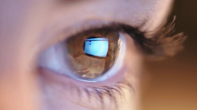 Close-up of a girl's eye looking at a laptop monitor and searching for information on the Internet, reflection in the eye, Intense Gaze of a Woman Seeking Information Online