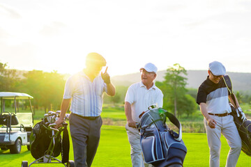Group of Asian businessman and senior CEO holding golf bag walking on golf course with talking...