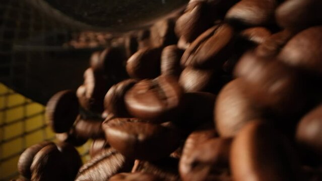The coffee beans rotate uniformly in the iron cage. Beauty close-up shot for commercials. The process of processing coffee beans into finished products