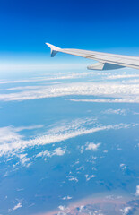 View from the airplane window at a beautiful cloudy sky and the airplane wing