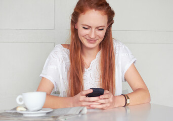 Coffee shop, phone and happy woman texting, relax and smile for chat app on wall background. Cafe, social media and female customer reading post, news or update while enjoying day off and tea break