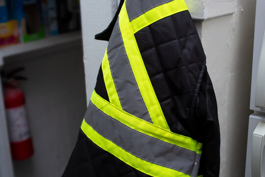 A view of a hi-vis utility jacket hanging on a wall hook.