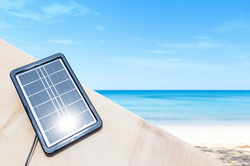 Portable solar cell panel over beautiful beach background, green energy concept, sustainability,...