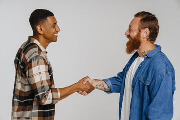 Two happy men smiling and shaking their hands while standing isolated