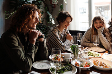Group of cheerful friends talking while dining in restaurant