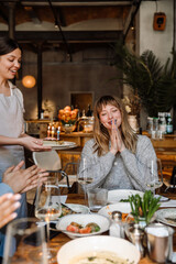 Cheerful blonde woman celebrating birthday in restaurant