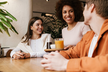 Smiling waitress serving drinks for couple in cafe