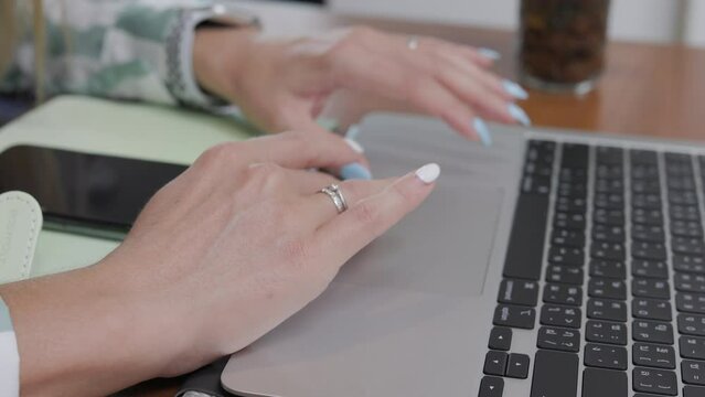 In a close-up side view, the hands of a businesswoman, representing a professional user, work diligently on a laptop keyboard at her home office desk, highlighting the concept of online technology.