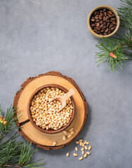 Pine nuts in a bowl  on a blue background with branches of pine needles. The concept of a natural,...