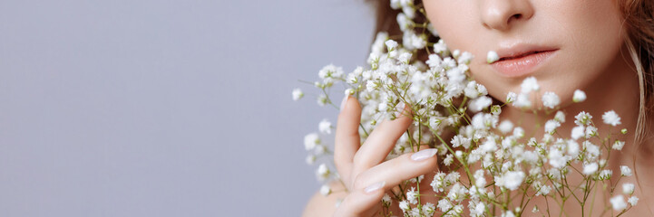 Part of the face of a beautiful blonde woman with perfect skin and a bouquet of white gypsophila...