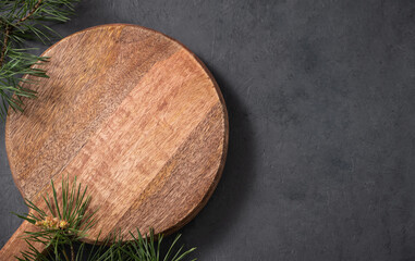 Fototapeta na wymiar Empty wooden board on dark texture background with fir tree branch. Cutting board for serving food or preparing homemade and healthy food.