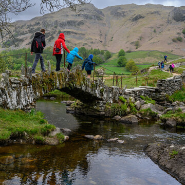 Walkers crossing a packhorse bridge in the Lake District