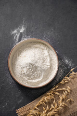 Oat flour is scattered on a dark background with napkin. Organic baking ingredients. Concept of homemade and healthy food.