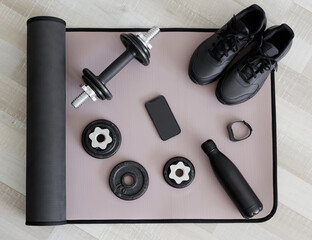 Dumbbells, shoes, water bottle, watch and phone on sport mat