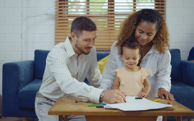 Dad, Mom and little daughter drawing with colorful pencils on paper happy smiling.Young family spend free time together in living room at home.