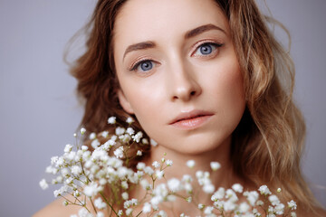 Portrait of a young beautiful blonde woman with white gypsophila flowers near her face. the concept...