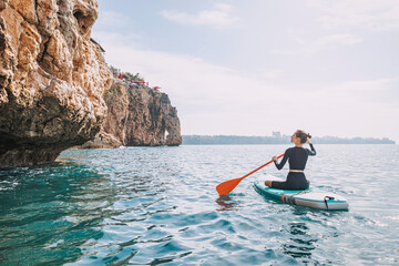 Happy girl in a swimsuit with a paddle swims on a SUP board on the sea in Antalya. Healthy lifestyle and recreation concept