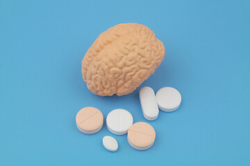 Human brain and medical pills on blue background. Medicine for mental health concept.