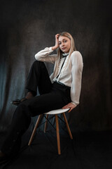 Fototapeta na wymiar Portrait of caucasian woman wearing white blouse sitting at chair isolated dark background