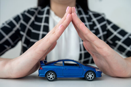 Small blue  toy car and female hand at office desk as insurance