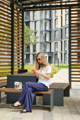 Woman sitting in gazebo on street with smartphone