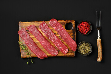 Overhead view of raw beef strips on black background