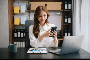 Young attractive Asian woman smiling thinking planning writing in notebook, tablet and laptop working from home at office .