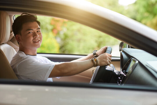 Happy Young Asian Man Driving Car On Sunny Day